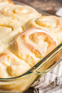 a casserole dish filled with cinnamon rolls covered in icing and sitting on a table