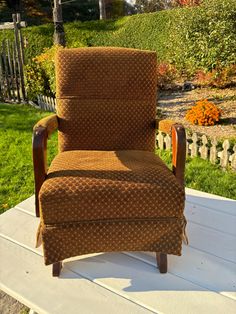 a brown chair sitting on top of a white wooden table next to a green field