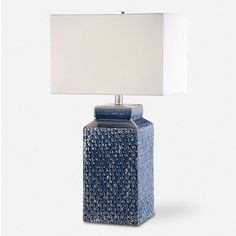 a blue ceramic table lamp with a white shade on the base and a square shape