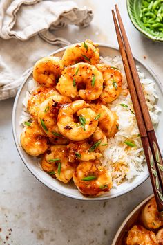 shrimp and rice in a bowl with chopsticks next to it on a table