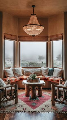 a living room filled with furniture and a round table in front of two large windows