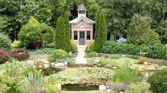 a small building surrounded by lots of trees and flowers in the middle of a garden