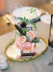 pink flowers in a glass vase on a gold plate with silverware and napkins