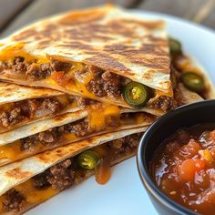 quesadillas stacked on top of each other with salsa in a bowl next to it