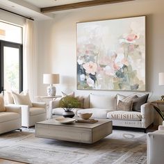 a living room filled with furniture and a large painting on the wall above it's windows