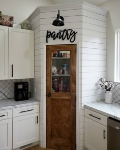 a kitchen with white cabinets and black lettering on the door that says pantry above it