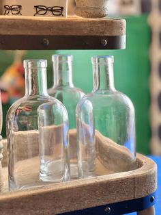 three glass bottles sitting on top of a wooden tray