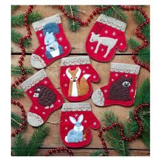 christmas stockings with animals and deers hanging from them on a wooden table next to pine branches