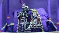 two people dressed in costume standing next to each other with purple curtains behind them,