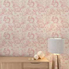 a lamp on a table next to a wallpaper with rabbits and flowers in pink