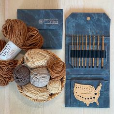 yarn and knitting needles sitting in a basket next to a pair of crochet hooks