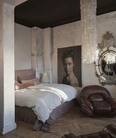 a bedroom with a bed, chair and pictures on the wall in it's corner