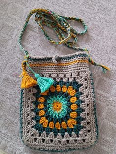 a crocheted granny bag with tassels on it sitting on a bed