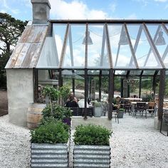 two large planters sitting in front of a building with glass walls and windows on the roof