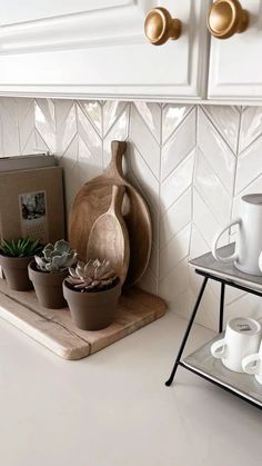 a kitchen counter topped with pots filled with succulents and coffee mugs