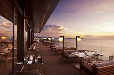 an outdoor dining area overlooking the ocean at sunset