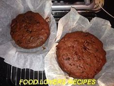 two chocolate muffins sitting on top of paper in front of a toaster oven