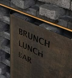 a sign that reads brunch lunch bar next to a brick wall with gold bars