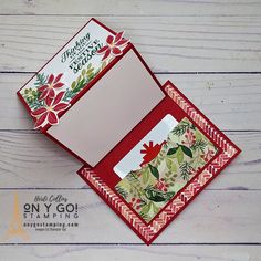 an open red and white card with floral designs on it, sitting on a wooden surface