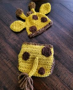 two crocheted hats and diaper covers on a wooden floor, one with a giraffe pattern