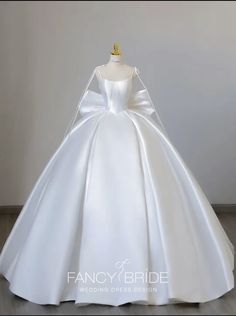 a white wedding dress on display in front of a wall