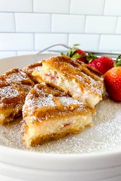 two pieces of french toast on a white plate with strawberries and powdered sugar