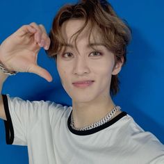 a young man is posing for the camera with his hand up to his head and wearing a white t - shirt