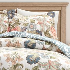 an image of a bed with floral comforter and pillow set on it's headboard