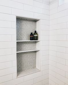 a white tiled shower with shelves in the corner