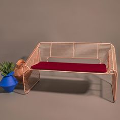 a chair with a red cushion next to a potted plant and a blue vase