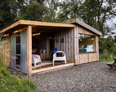 a small wooden shed with two chairs outside