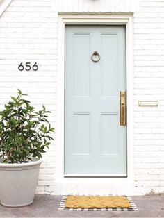 a white house with a blue front door and numbers on the side walk next to a potted plant