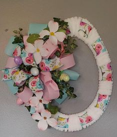 a wreath decorated with flowers and ribbons hanging on the side of a wall in a room