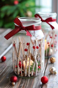 two mason jars filled with candles on top of a wooden table next to christmas decorations