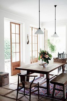 a dining room table with two benches and flowers in a vase on the table next to it