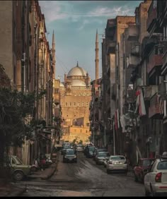 an old city street with cars parked on both sides and tall buildings in the background