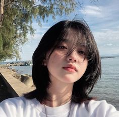 a woman standing next to the ocean wearing a white shirt