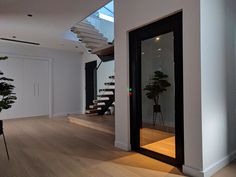 an empty room with stairs leading up to the second floor and potted plants on the far side