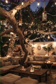 an outdoor seating area is lit up with fairy lights and hanging mason jars on the tree