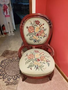 a chair with flowers painted on it sitting in front of a red wall next to a rug