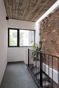 an empty room with a brick wall and metal railings next to a potted plant