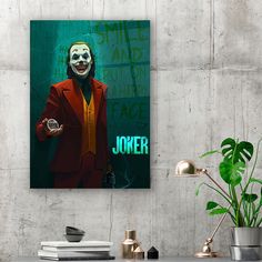 the joker movie poster is displayed on a wall next to a potted plant