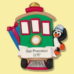 a green train ornament with a penguin holding a sign that says san francisco