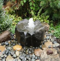 a water fountain surrounded by rocks and trees