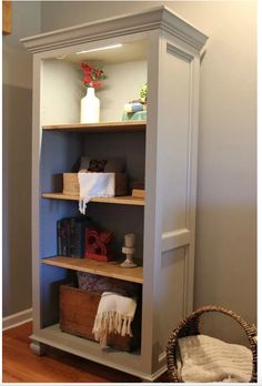 an open bookcase in the corner of a room next to a basket and flowers