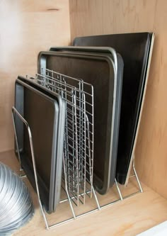 there are many plates and pans on the shelf in this kitchen cabinet with metal racks