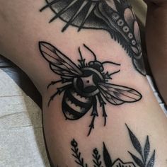 a black and white photo of a bee on someone's leg