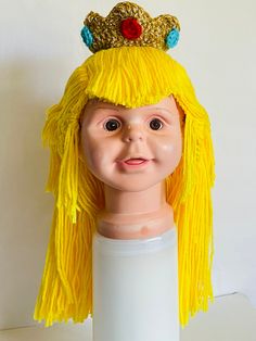 a doll head wearing a yellow wig and a crown on top of it's head