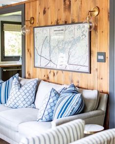 a living room with wood paneling and white couches in front of a map on the wall