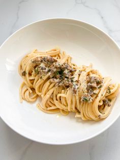 a white plate topped with pasta covered in sauce